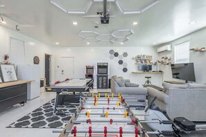 A modern living room with a foosball table, a treadmill, and a sofa.