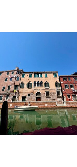 A row of historic buildings with arched windows and a canal in the foreground. - Laguna Loft (Venezia)