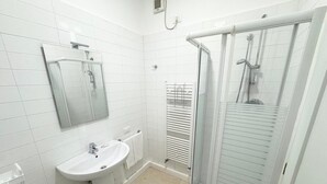 A modern bathroom with a sink, mirror, and glass-enclosed shower.