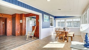 A spacious room with a wooden floor, a dining area with a table and chairs, and a large window providing natural light.