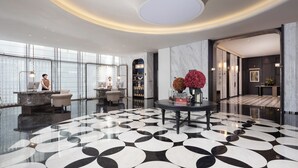 A modern lobby with a marble floor, reception desk, and a round table with flowers. - Wanda Yi Hangzhou East Railway Station (Hangzhou)