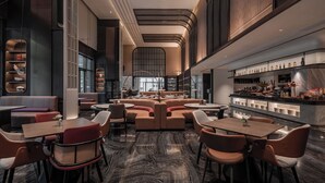 A modern restaurant with high ceilings, a central seating area, and a bar with shelves of bottles. - Wanda Yi Hangzhou East Railway Station (Hangzhou)