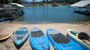 Vista del lago con puestas de remo en la orilla, un muelle y un bote al fondo.