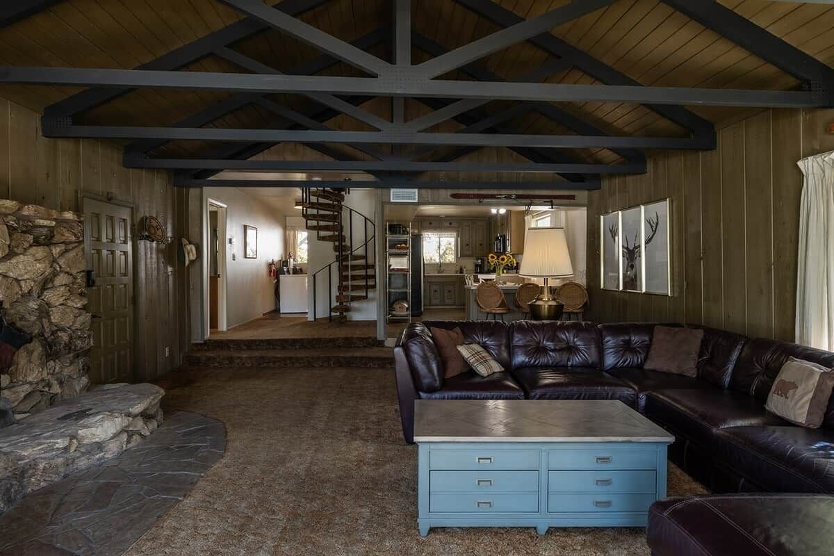 Una sala de estar acogedora con chimenea de piedra, un sofá de cuero tipo seccional y una mesa de centro azul.