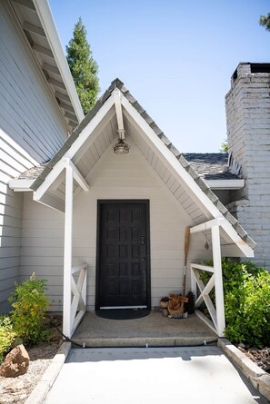 Ein Haus mit schwarzem Eingang, weißer Veranda und einem kleinen Garten.