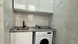 A compact kitchen with a built-in washing machine, a sink, and a countertop with a toaster.