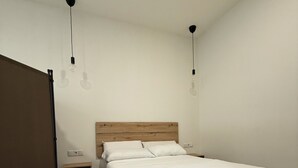 A single-bed room with a wooden headboard, a bedside table, and a nightstand.