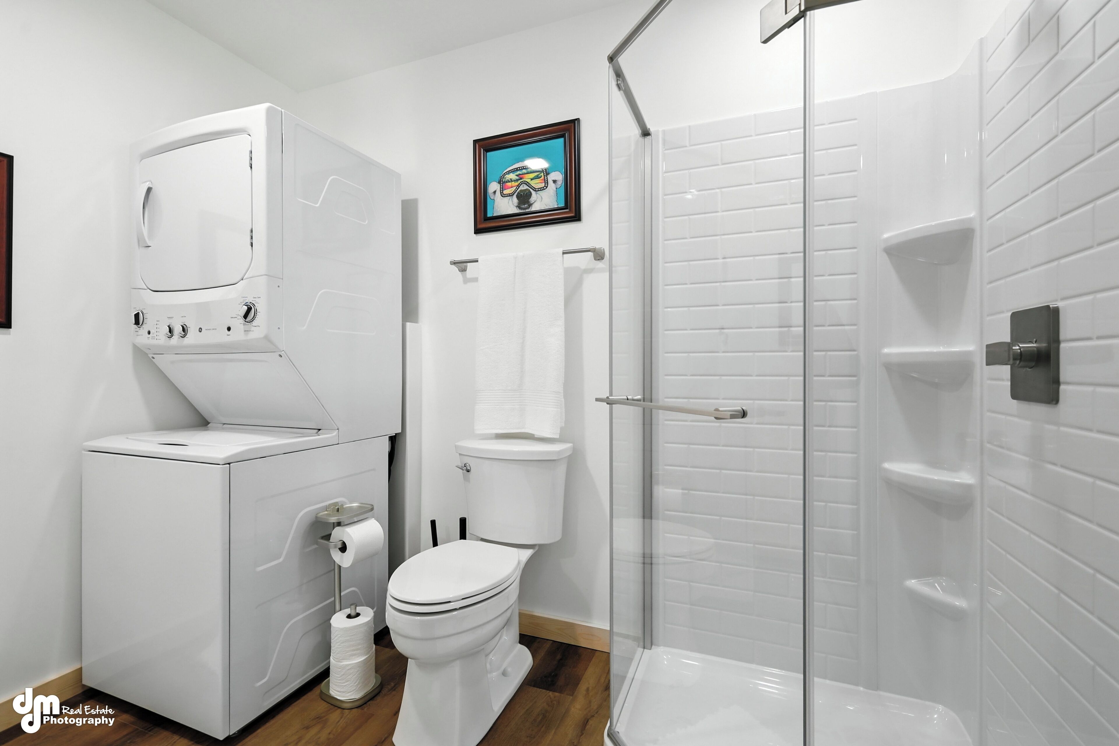 A modern bathroom with a built-in washer and dryer, a toilet, and a glass-enclosed shower.