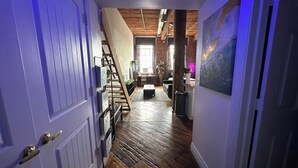 A hallway with wooden flooring, a staircase, and a painting on the wall.