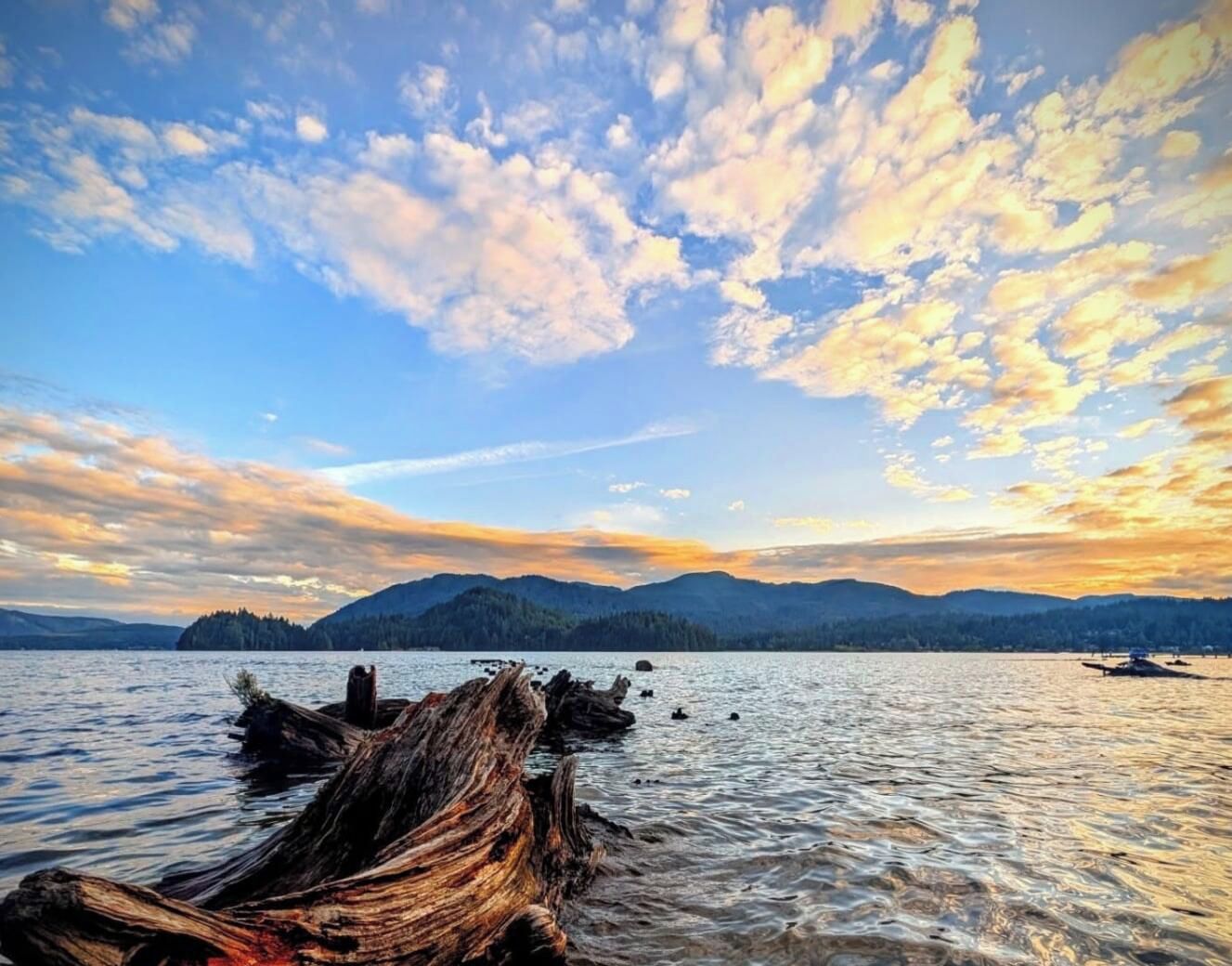 Un lac paisible, avec une structure en bois au premier plan et des montagnes en arrière-plan.