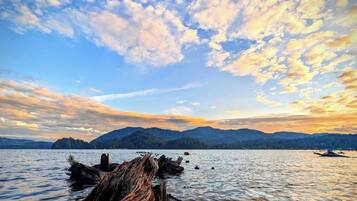 Un lac paisible, avec une structure en bois au premier plan et des montagnes en arrière-plan.