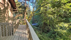 A wooden deck with a railing overlooking a dense forest. - Sudden Valley Retreat 3BR House -Steps to Lake Louise (Bellingham)