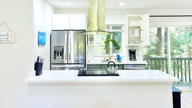 A modern kitchen with a central island, stainless steel appliances, and a view of the outdoors. - Sudden Valley Retreat 3BR House -Steps to Lake Louise (Bellingham)