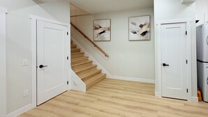 A modern interior with a wooden staircase, white walls, and a laundry area. - Sudden Valley Retreat 3BR House -Steps to Lake Louise (Bellingham)