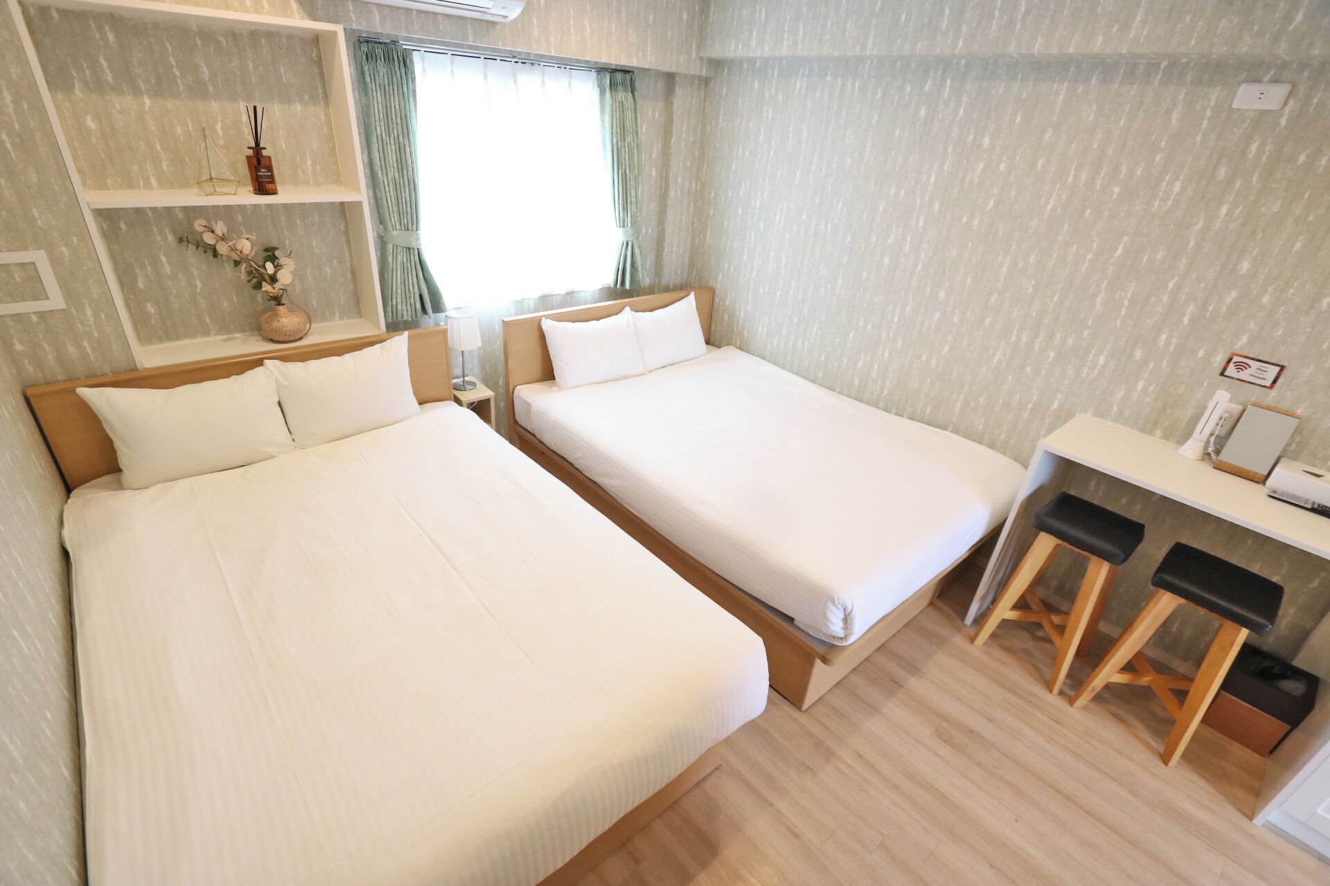 A double room with two beds, a small desk, and a chair.