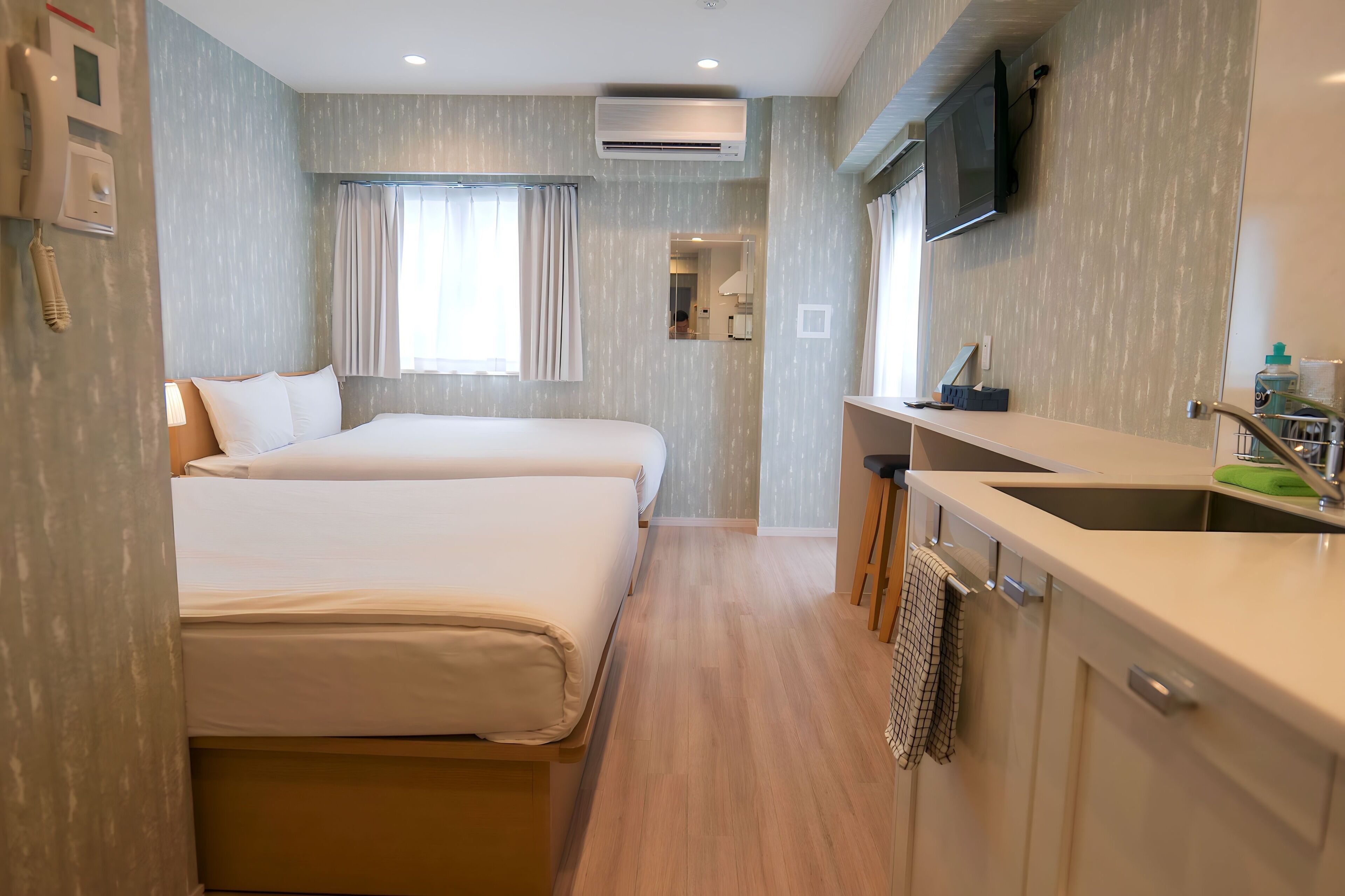 Een hotelkamer met een bed, een kitchenette met een spoelbak en een spiegel.