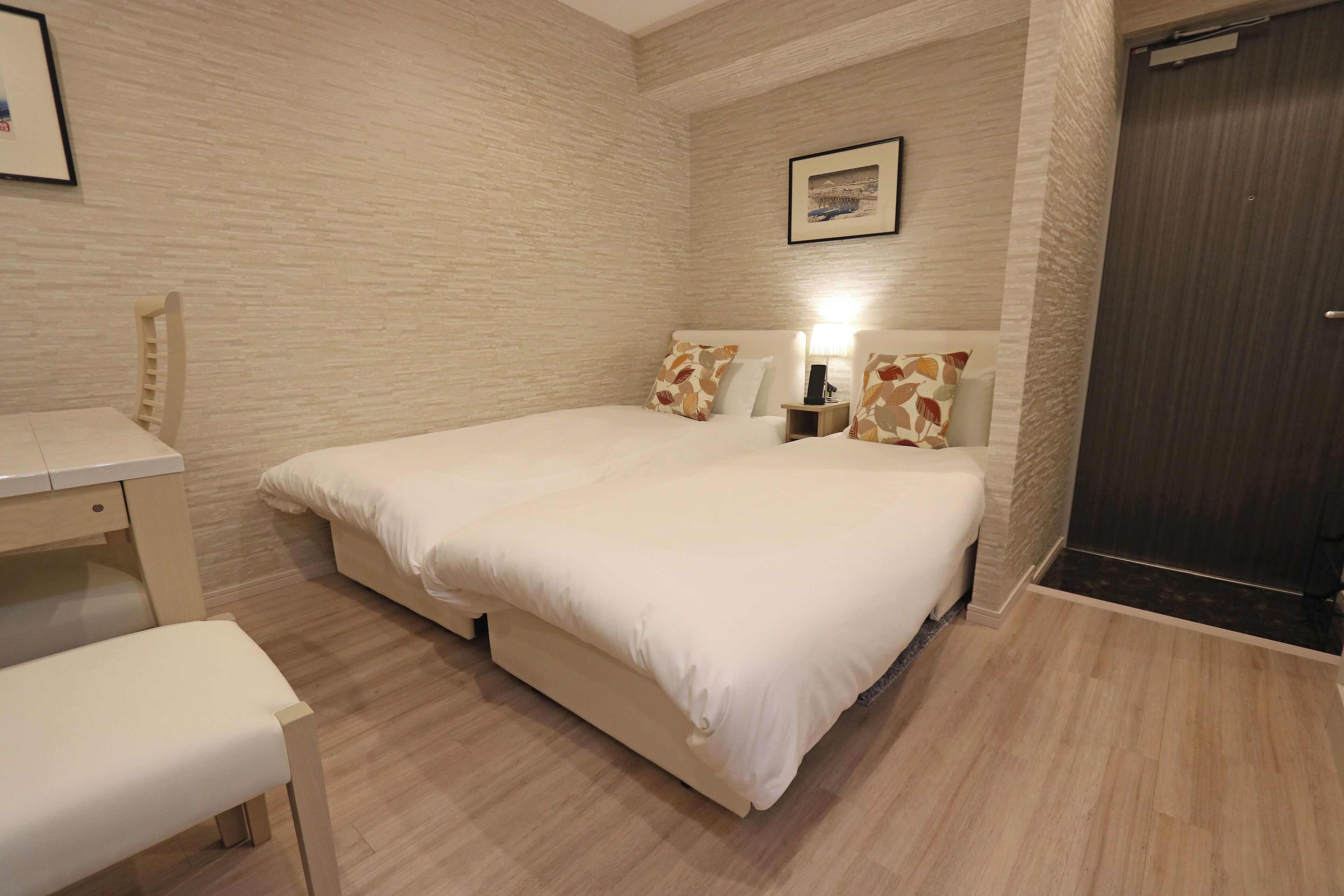 A neatly arranged bedroom with a bed, bedside table, lamp, and a chair.