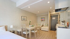 Habitació d'hotel amb un llit, taula de menjador amb cadires, zona de cuina petita i bany.