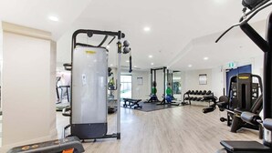 Ein Fitnessstudio mit verschiedenen Trainingsgeräten, darunter ein Squat-Rack, Bänke und Kurzhanteln.