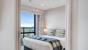 Ein modernes Schlafzimmer mit einem großen Bett, Blick auf die Stadt und einem Balkon.