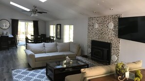 A modern living room with a sofa, coffee table, and fireplace. There is a dining area with a table and chairs in the background. - Best of both worlds, nature and Chambers landing (Tahoma)