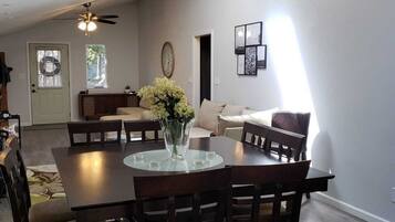 A dining area with a round table, chairs, and a ceiling fan.