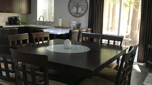 A modern kitchen with dark wooden cabinets, a central island, and a dining area with a round table and chairs. - Best of both worlds, nature and Chambers landing (Tahoma)