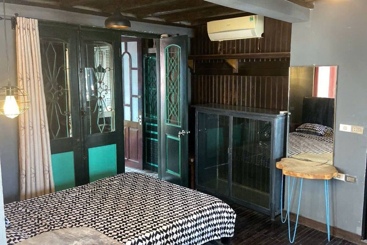 Una habitación con cama, una mesita, un armario y una puerta con espejo.
