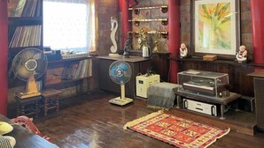 A rustic room with exposed wooden beams, a fireplace, a bookshelf, and a vintage radio. - Phuong Maison d'Art (Hanoi)