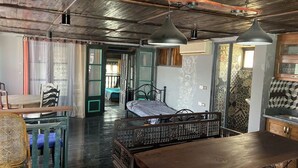 A rustic room with a wooden ceiling, a bed with a metal frame, a dining table, and a chair. - Phuong Maison d'Art (Hanoi)