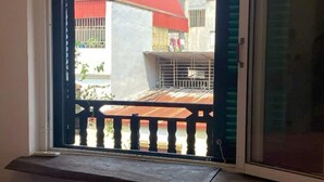 A room with a window overlooking a balcony with a red roof and a metal railing. - Phuong Maison d'Art (Hanoi)