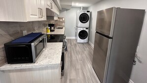 A compact kitchen with a microwave, double washing machine, and a stainless steel refrigerator. - Whitby Hideout - 3BR 5BD 3WR Pool Table Sauna close to Thermea SPA (Whitby)