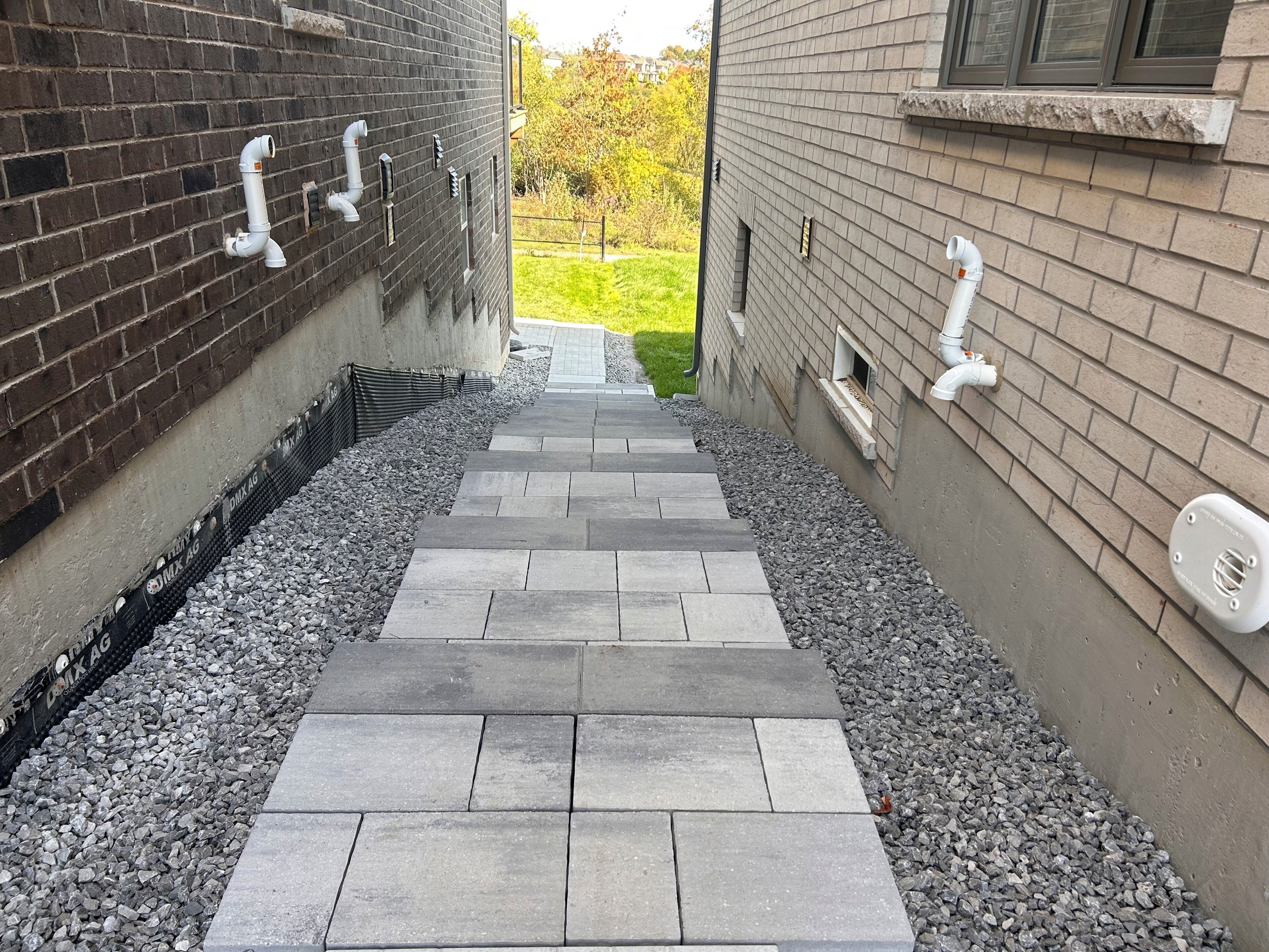 Un chemin menant à un bâtiment dont la façade est en briques et qui possède une fenêtre.