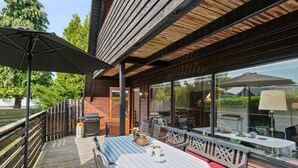 An outdoor patio with a table and chairs, a grill, and a wooden deck. - "Hildegunda" - 280m from the sea by Interhome (Nexø)