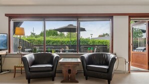 A room with two leather chairs, a small table, and large windows offering a view of greenery and a building. - "Hildegunda" - 280m from the sea by Interhome (Nexø)