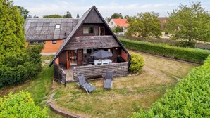A wooden A-frame house with a patio area, including two lounge chairs and a table. - "Hildegunda" - 280m from the sea by Interhome (Nexø)