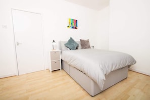 A bedroom with a bed, bedside tables, a door, and a colorful artwork on the wall. - Cosy 2BR Flat Near Anfield & Goodison, Liverpool (Liverpool)
