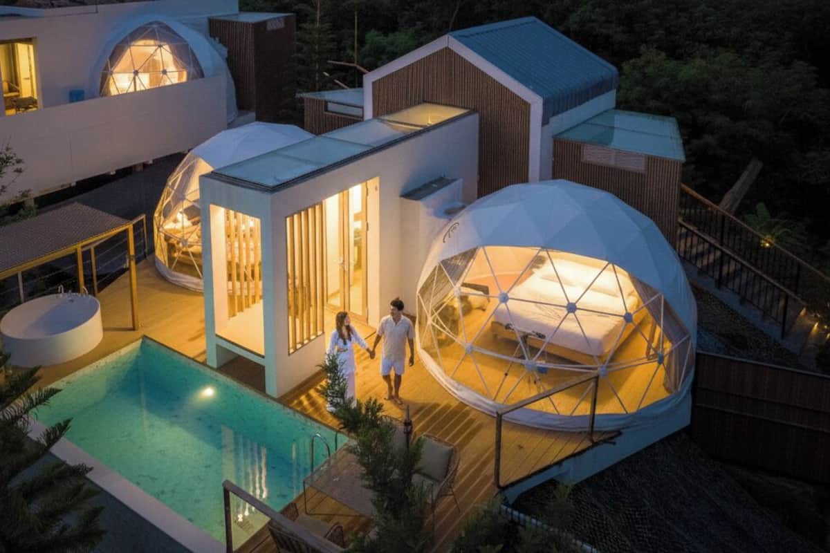 A modern house with a swimming pool, large dome-shaped structures, and a wooden deck.