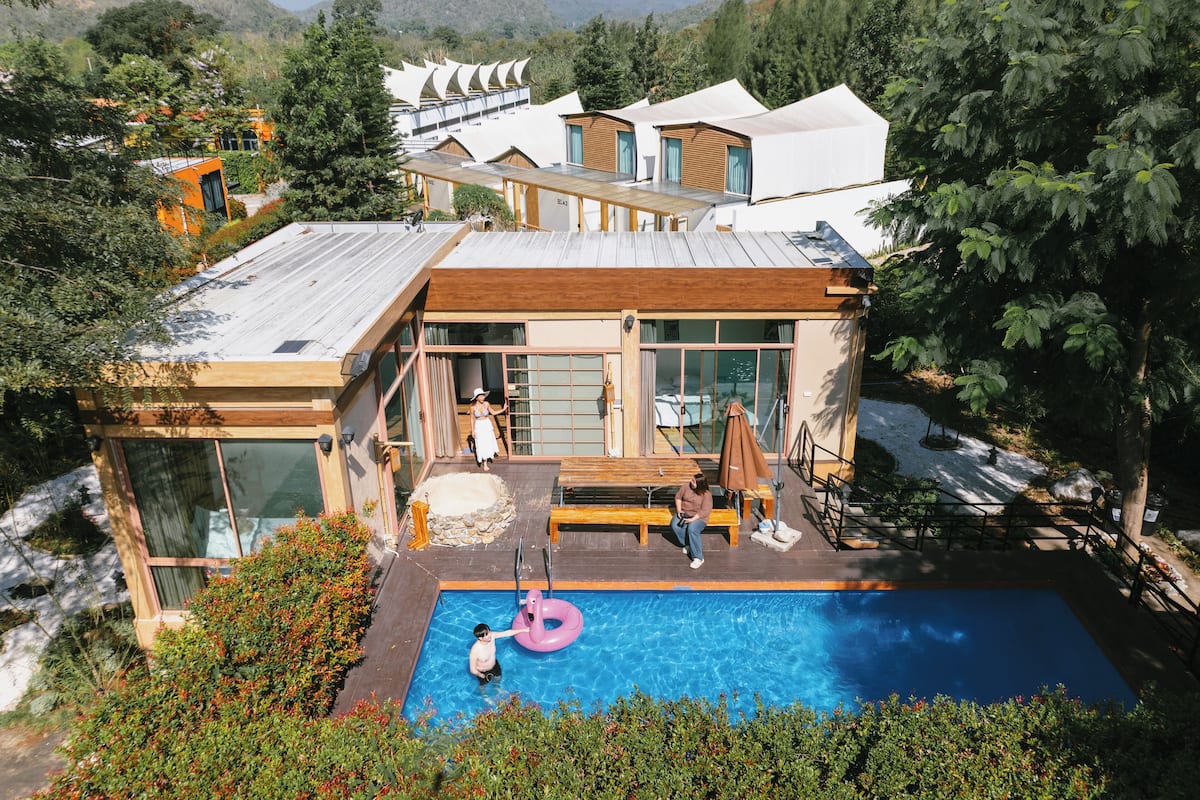 A modern house with a swimming pool, wooden deck, and large windows.
