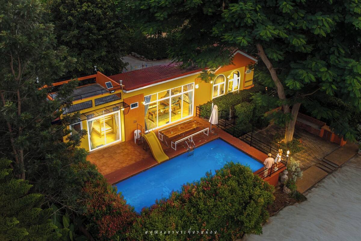 A two-story house with a swimming pool, large windows, and a covered patio area.