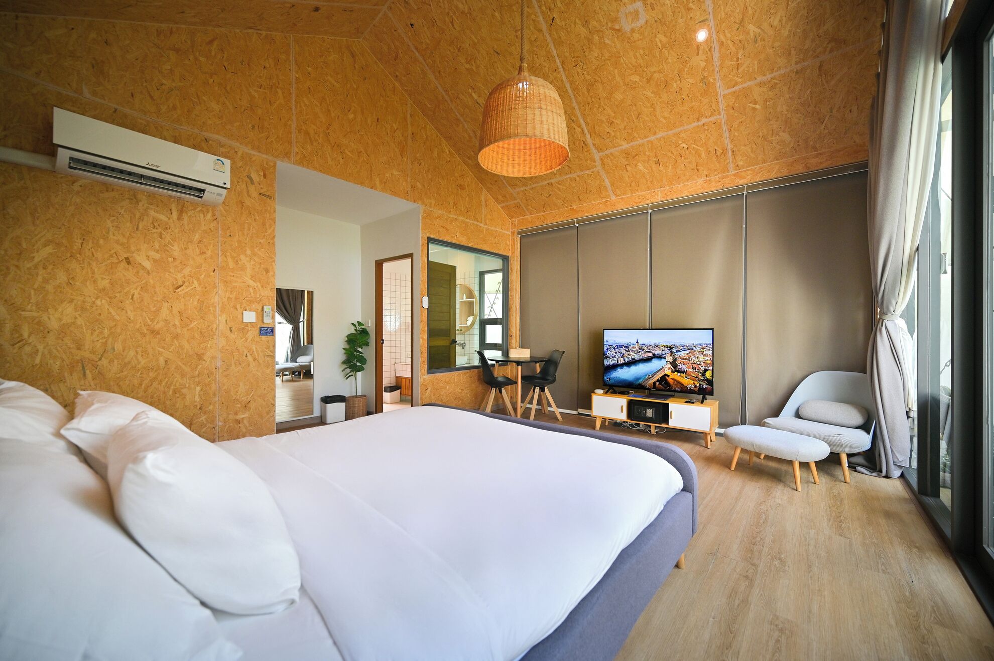 Una habitación de hotel moderna con una cama grande, televisión, escritorio y silla.