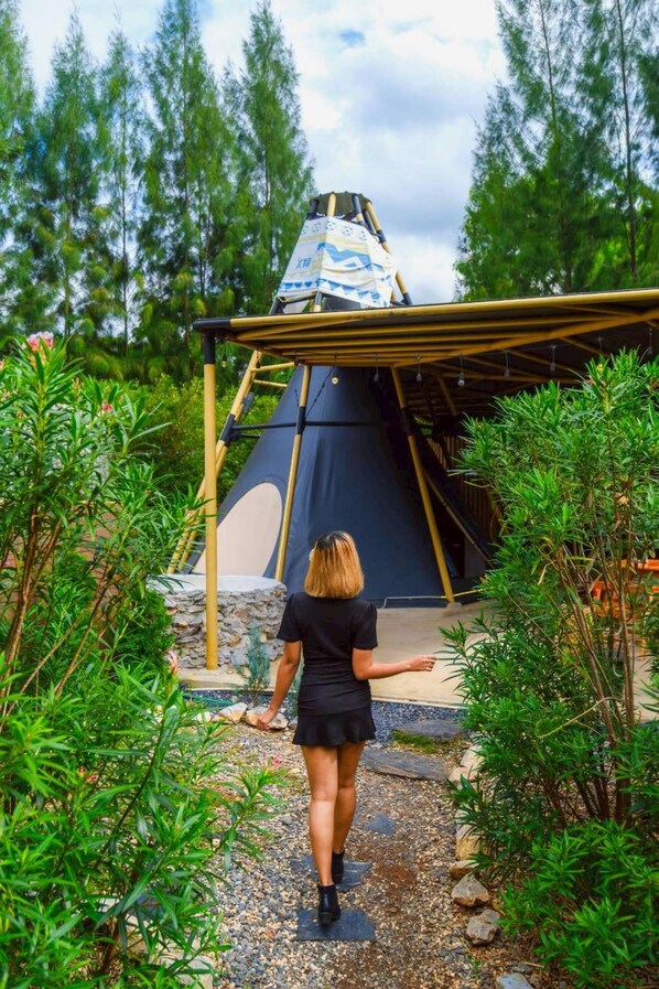 A person walking towards a large tent-like structure in a garden with dense greenery and a stone pathway. - TheX10 PrivatePoolVilla & ResortKhaoYai (Pak Chong)