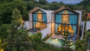 Ein modernes, zweistöckiges Haus mit Swimmingpool, großen Fenstern und einem Balkon.