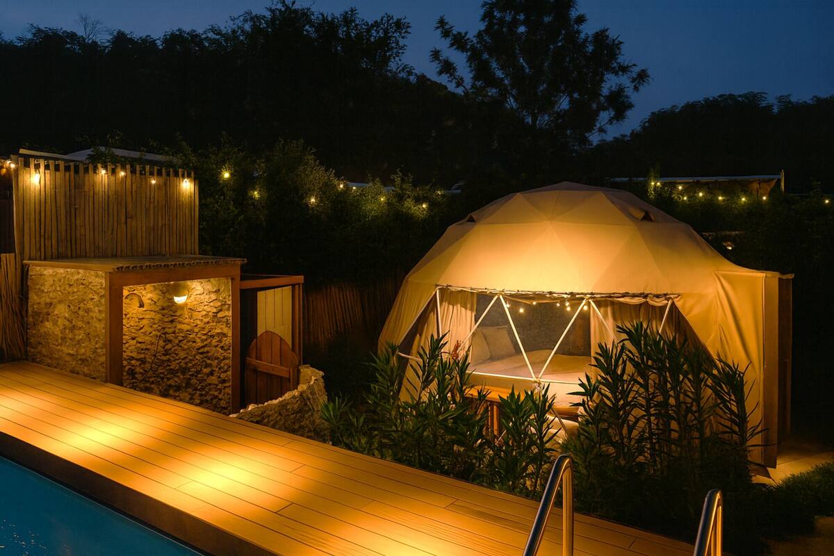 A tented outdoor area with a pool, stone structure, and string lights.