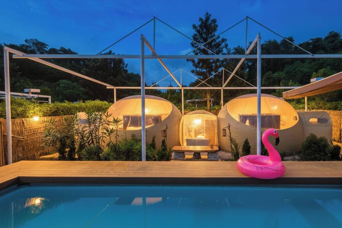 A pool area with three dome-shaped structures, a pink flamingo float, and a wooden deck.
