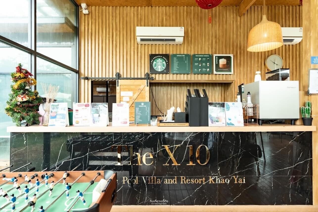 A reception desk with a foosball table, a clock, and a menu board at a hotel named 'The X10'.
