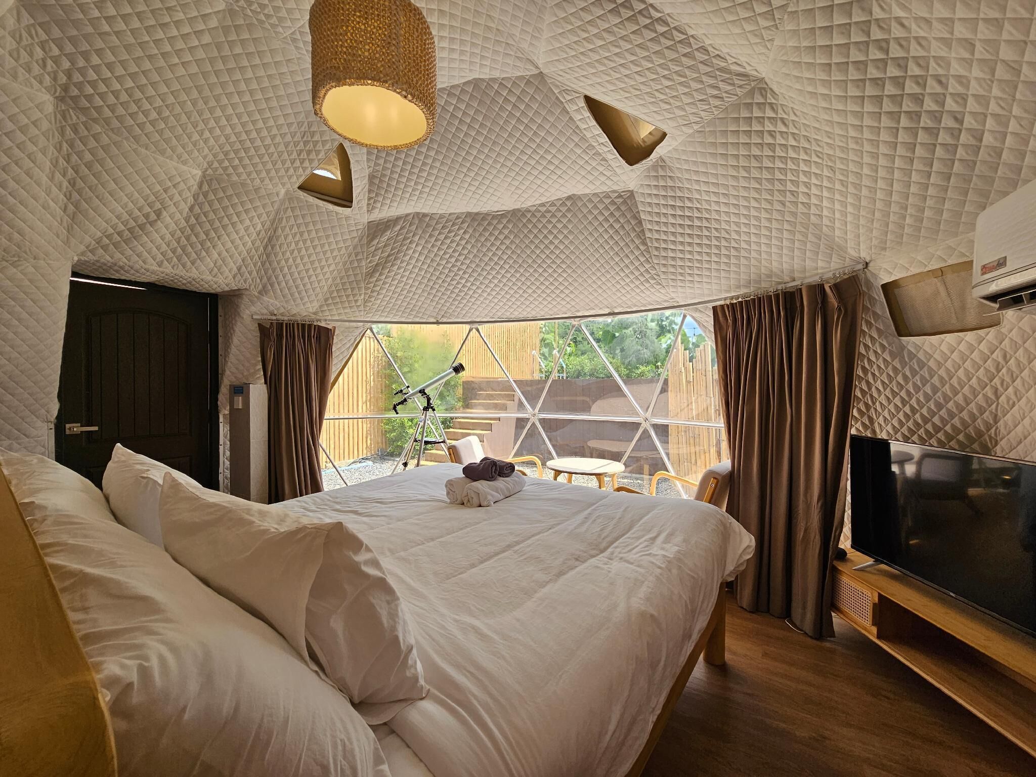 A bedroom with a large bed, a TV, and a telescope.