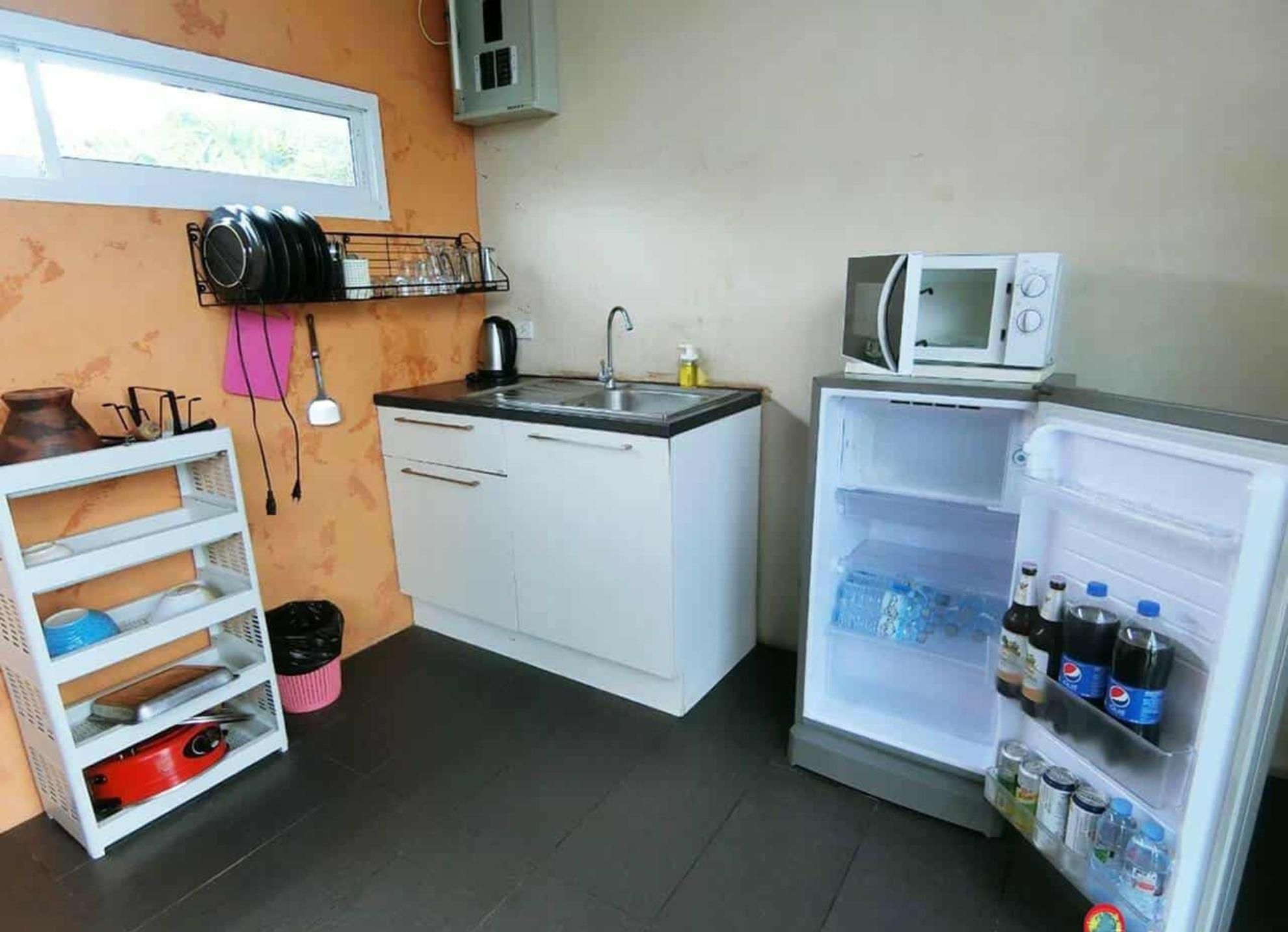 Une cuisine compacte équipée d’un four à micro-ondes, d’un réfrigérateur rempli de boissons, d’un évier et d’une fenêtre située au-dessus de l’évier.