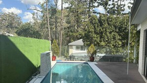 Una piscina rectangular con borde de piedra, rodeada por una terraza de madera.
