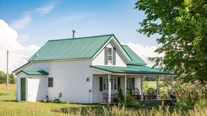 Une maison blanche avec un toit vert et une véranda.